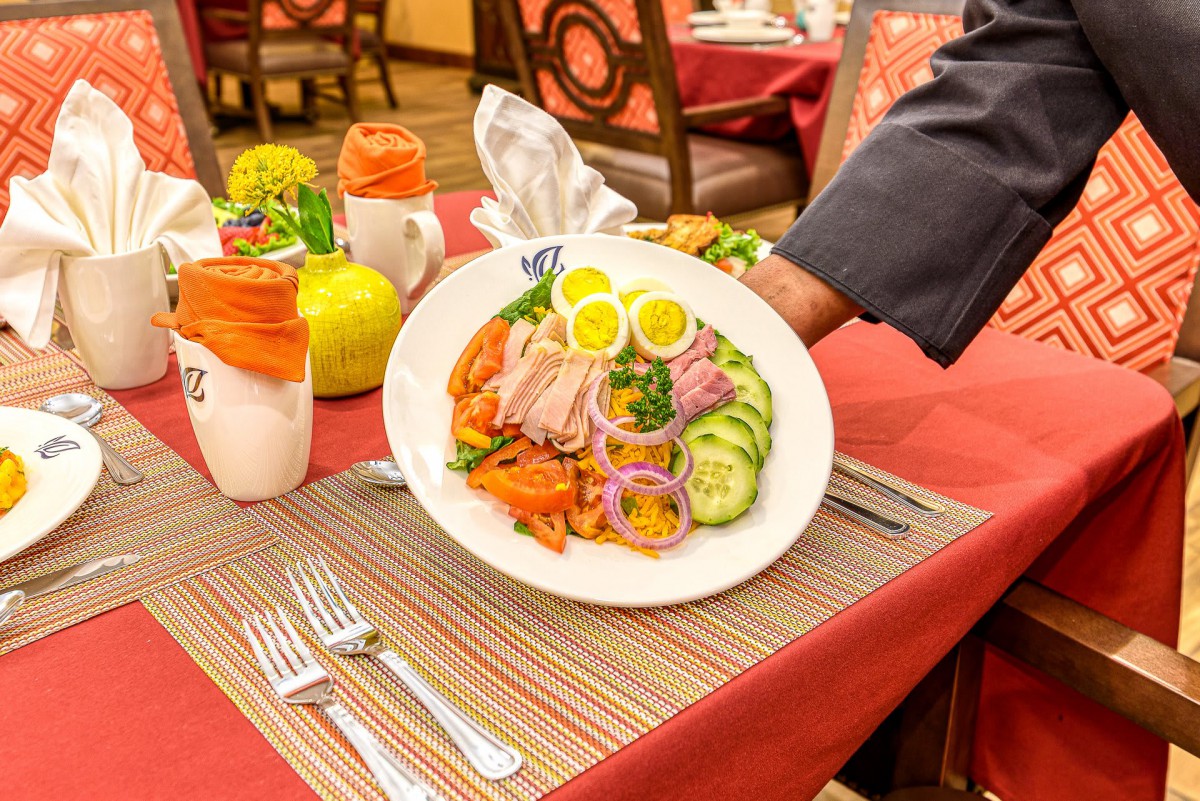 A colorful salad is being served in an elegant restaurant setting.