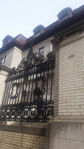 A detailed view of a decorative iron gate in front of a historical building.