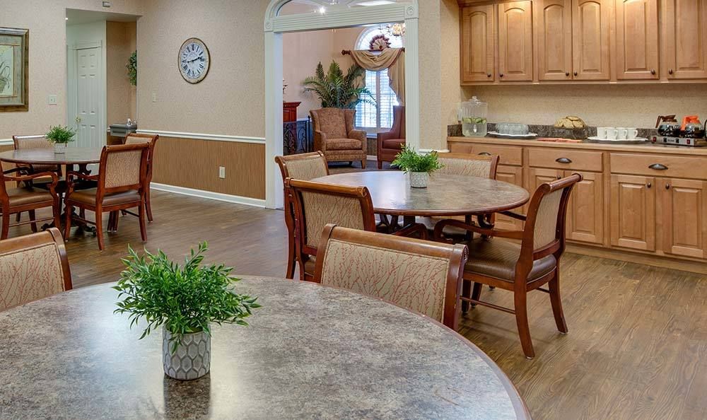 A cozy dining area with round tables, wooden chairs, and small potted plants.