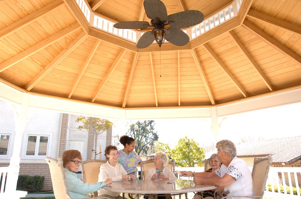 A group of seniors enjoying a gathering under a wooden gazebo.