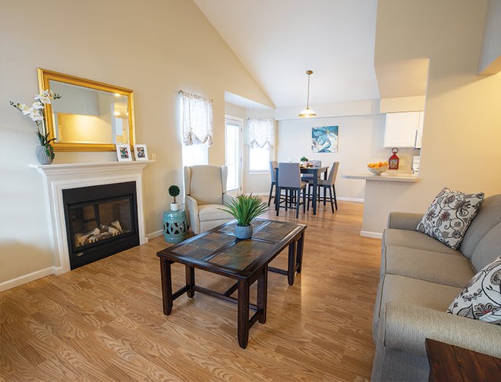 A cozy living room with hardwood floors, featuring a fireplace and an adjacent dining area.