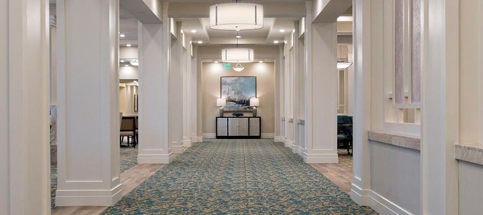 A well-lit hallway with a patterned carpet and wall decor.