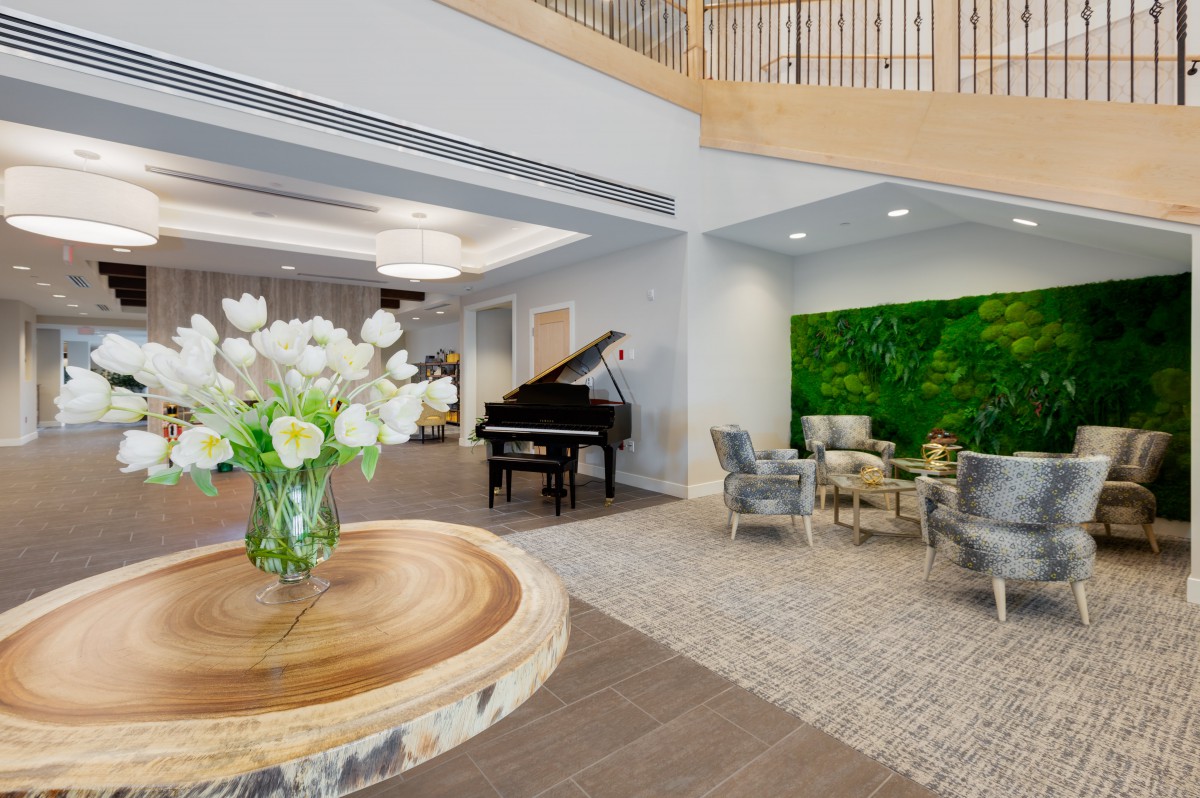 A modern lobby with a grand piano, elegant seating, and fresh flowers on a table.