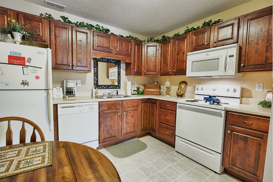 A cozy kitchen featuring wooden cabinets, white appliances, and charming decor.