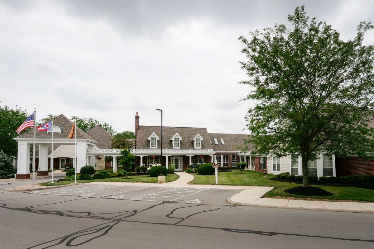 A suburban residential building with a cloudy sky and trees in the background.