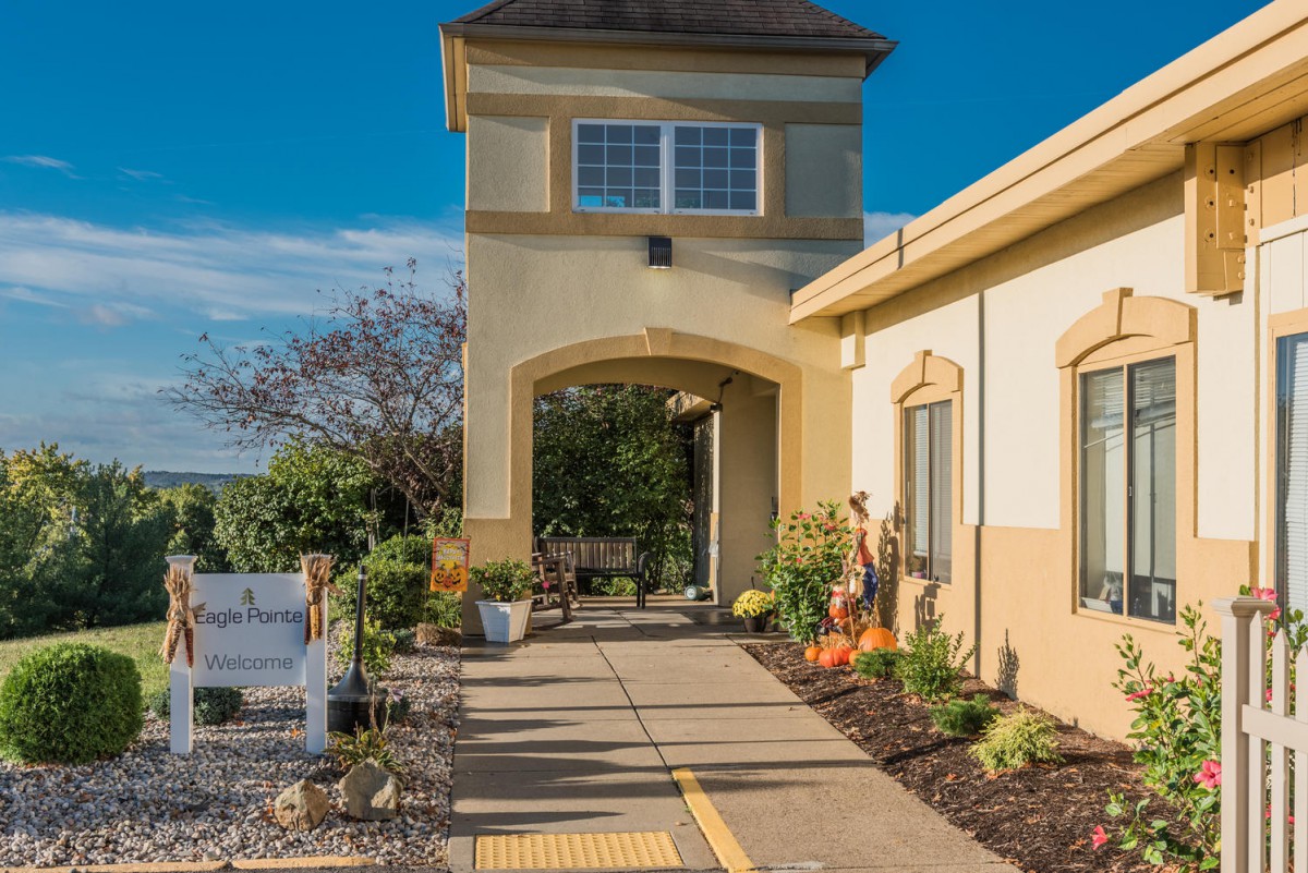 A building entrance with a landscaped pathway under a clear blue sky.