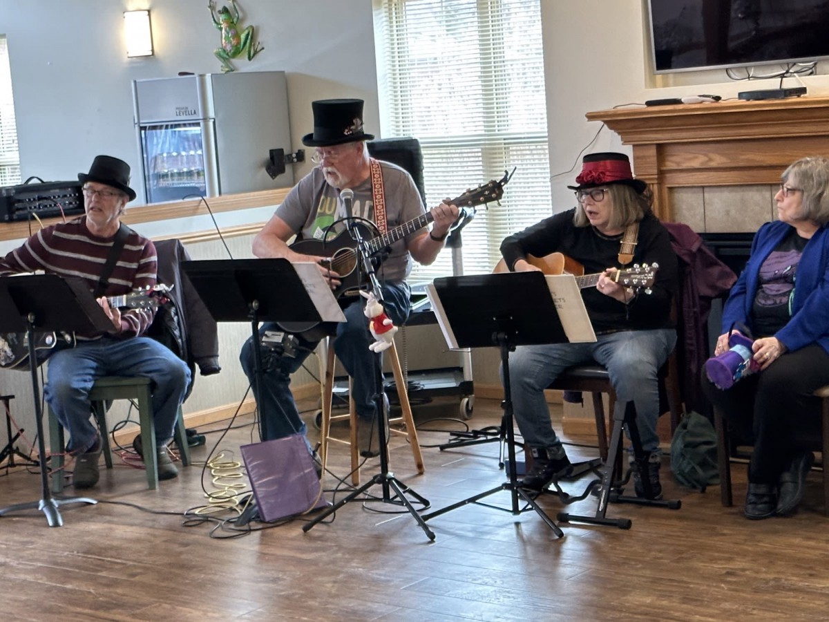 A group of musicians playing guitars indoors, wearing hats during a performance.