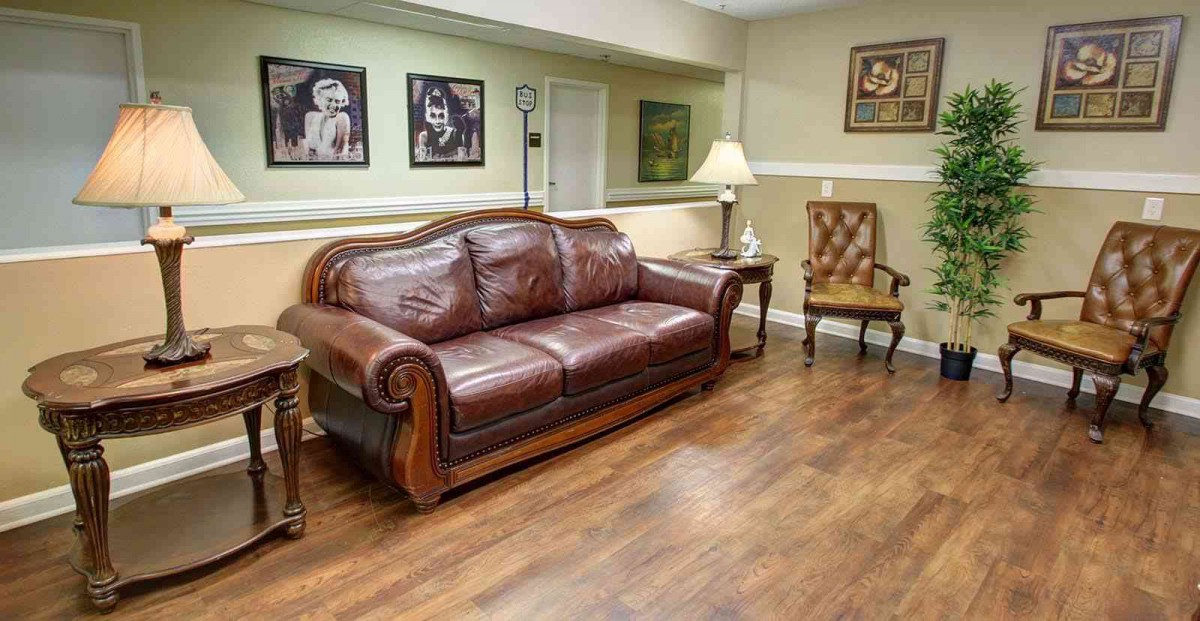 A cozy living room with a leather couch, wooden flooring, and decorative artwork.