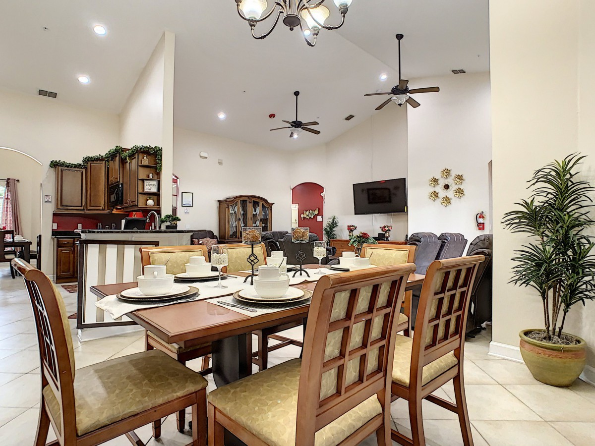 A modern dining area with a neatly set table, adjoining a cozy living space in an open-concept home.