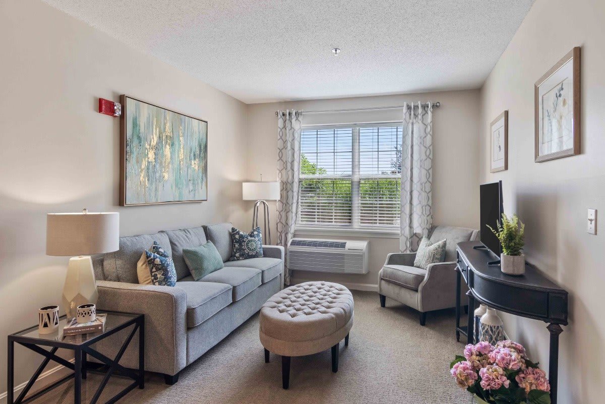 A cozy living room with a sofa, armchair, and a large window.