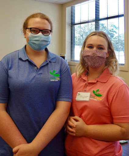 Two individuals wearing masks, posing together in a casual setting.