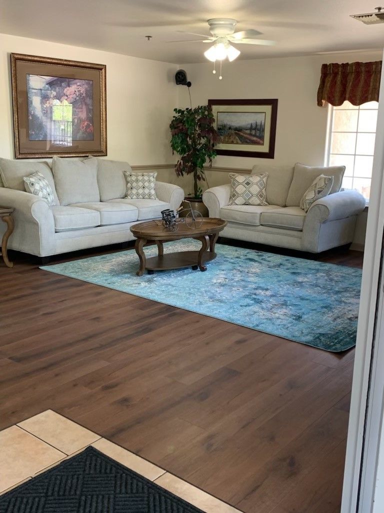 A cozy living room with two sofas, a coffee table, and a decorative rug on wooden flooring.
