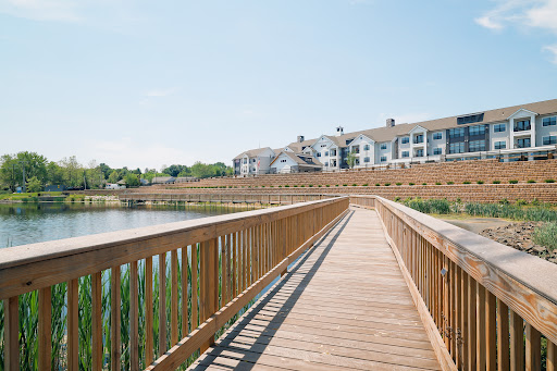 A serene wooden bridge leading towards a residential building by the water.