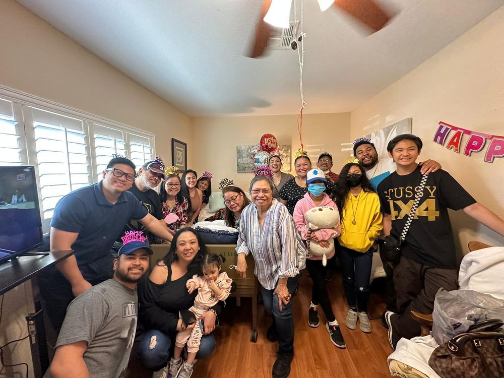 A joyful family gathering with everyone smiling for a group photo indoors.