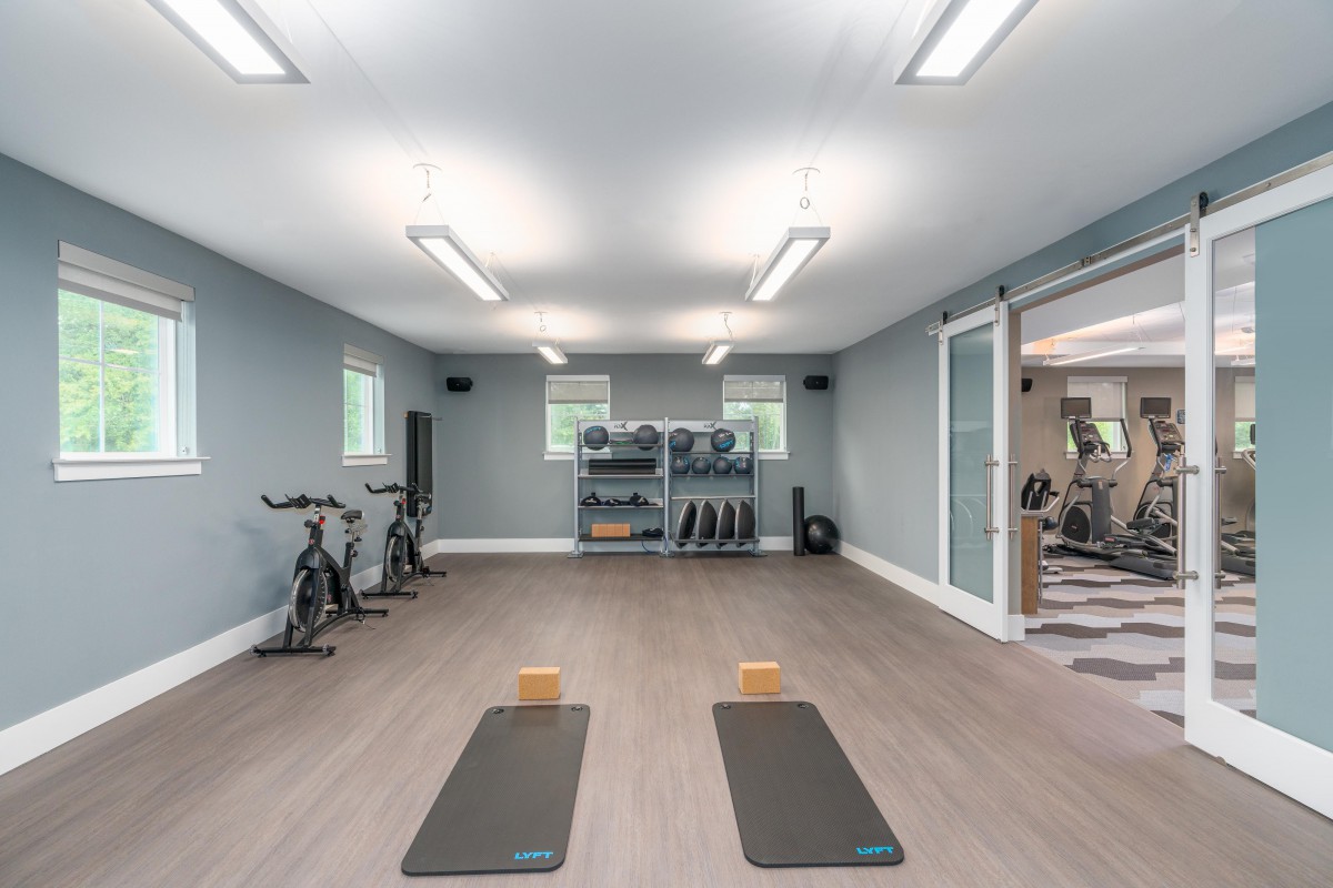A modern gym featuring yoga mats and exercise equipment in a well-lit indoor space.