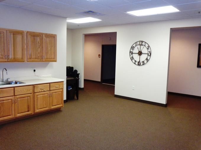 Empty office space with wall clock and wooden cabinets.