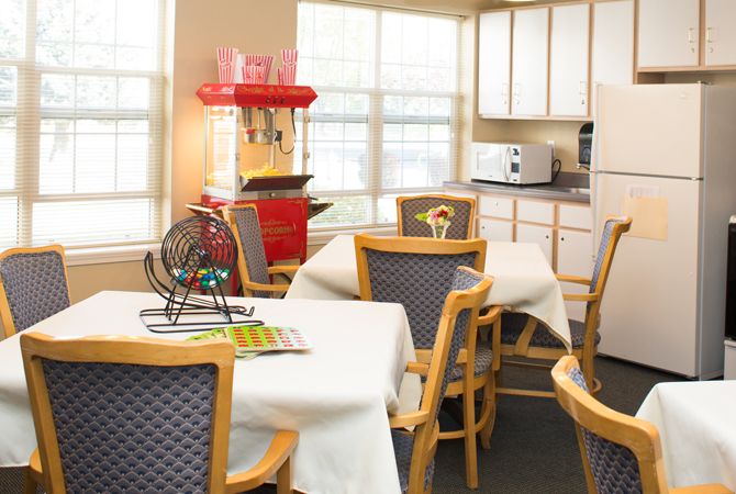 A cozy kitchen area with tables, chairs, a popcorn machine, and a bingo set.