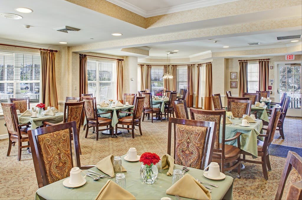 An elegant dining room with neatly arranged tables and chairs, adorned with decorative elements and natural light.