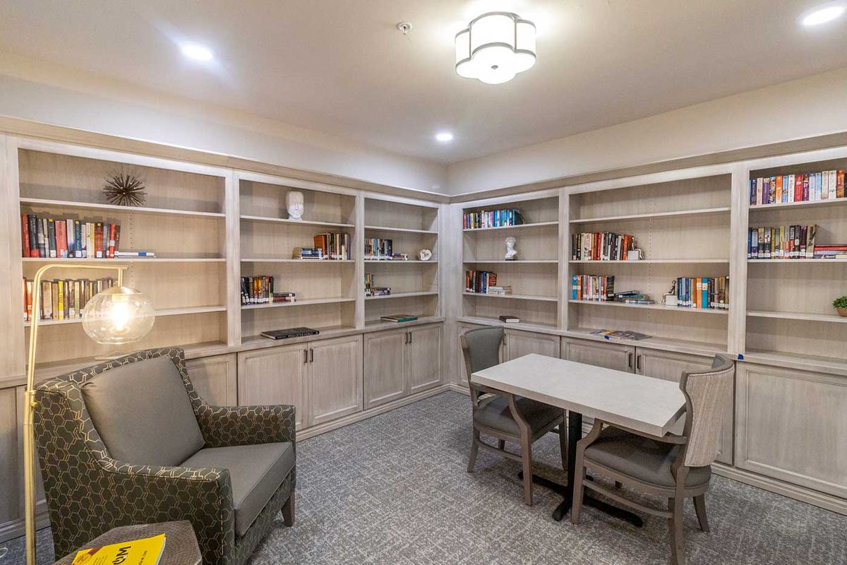 A cozy library with bookshelves, seating, and a table for reading.