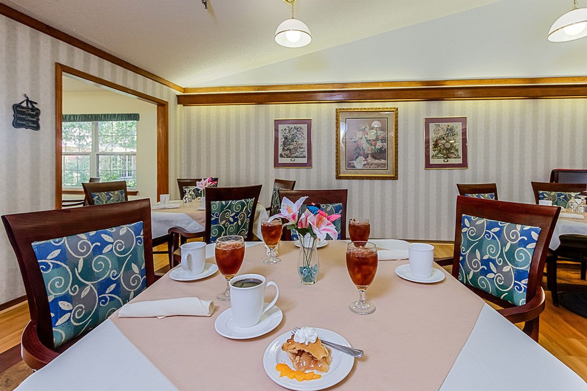 A cozy dining room featuring a table set with glasses and cups, surrounded by elegant decor.