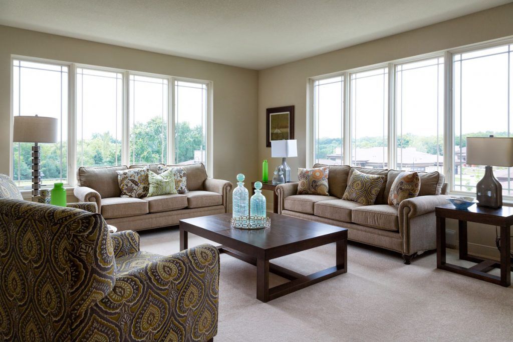 A cozy living room with large windows, two beige sofas, and a dark wood coffee table.