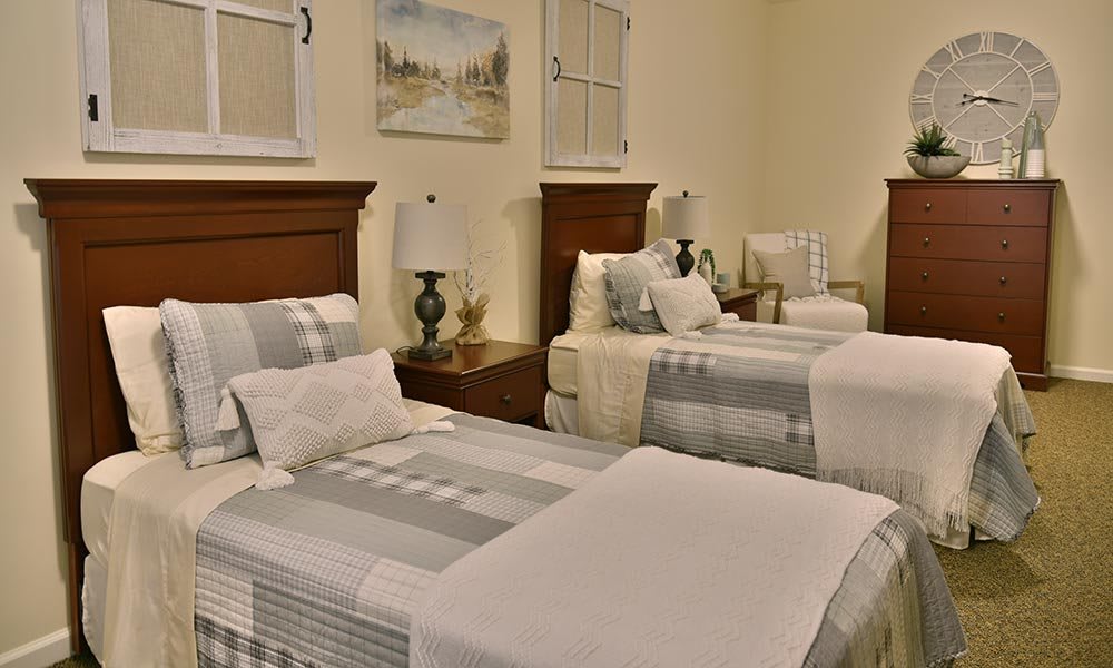 A cozy bedroom with twin beds, elegant lamps, and a comfortable armchair.