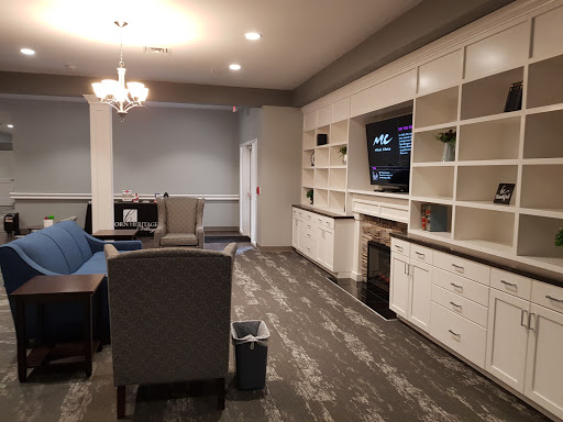 A cozy living room area featuring comfortable seating, a television, and stylish bookshelves.