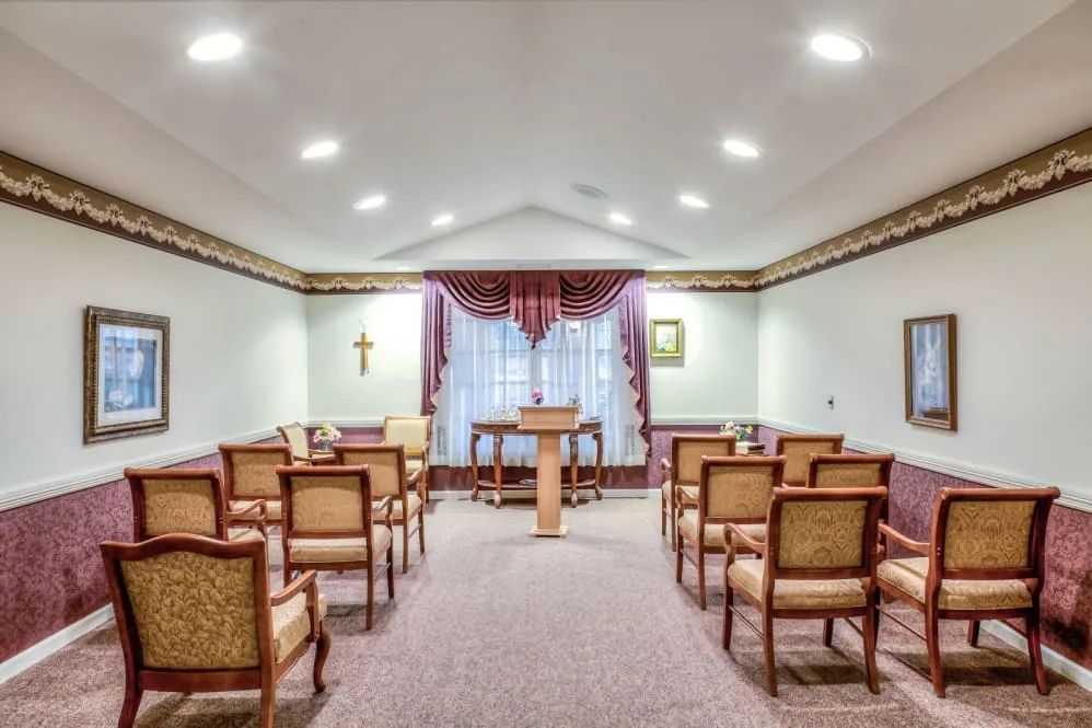 A small chapel interior featuring rows of chairs leading to an altar.
