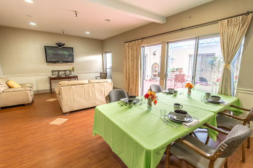 A cozy dining area featuring a green tablecloth, flowers, and an inviting living room in the background.