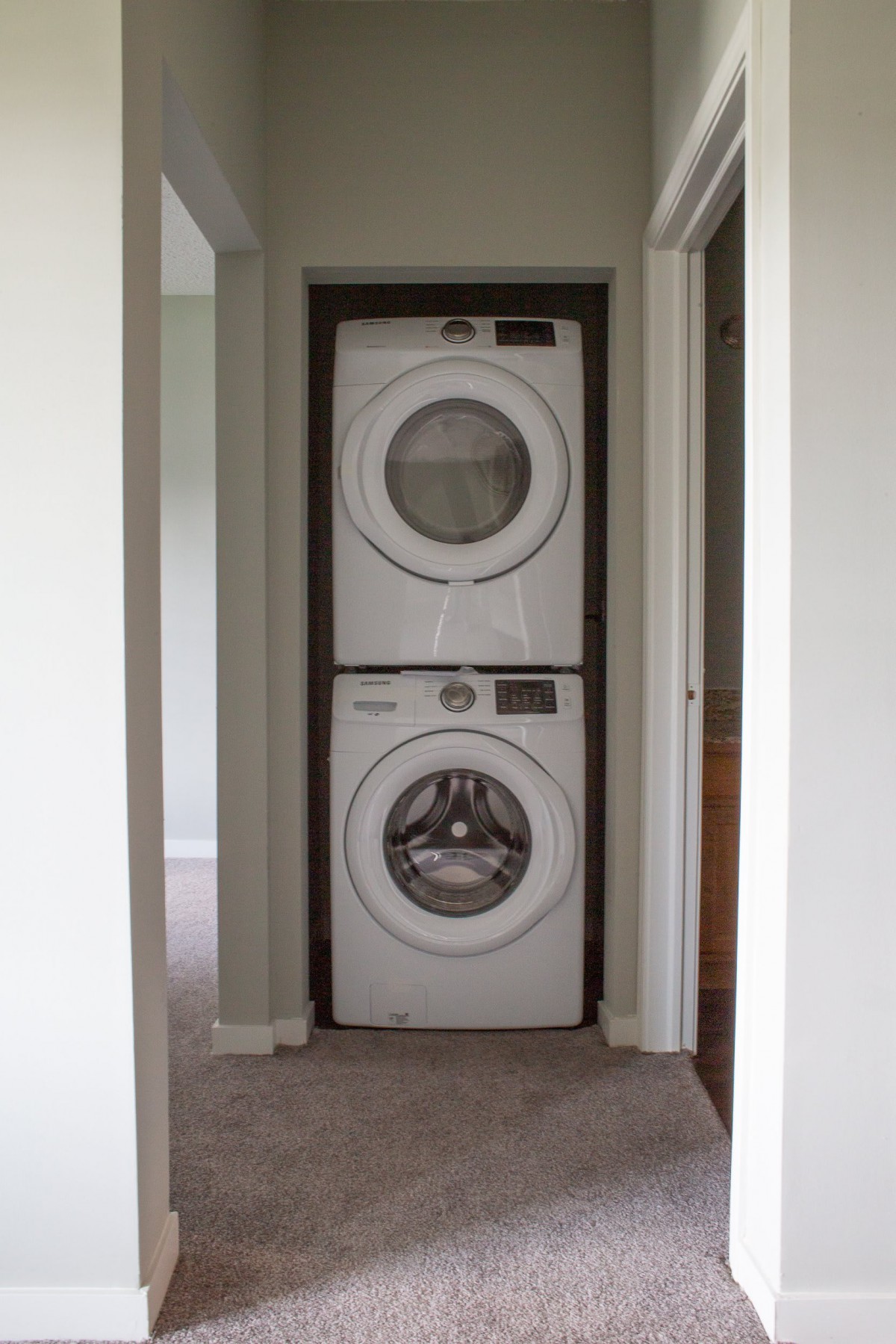 A stacked washer and dryer unit in a home hallway.