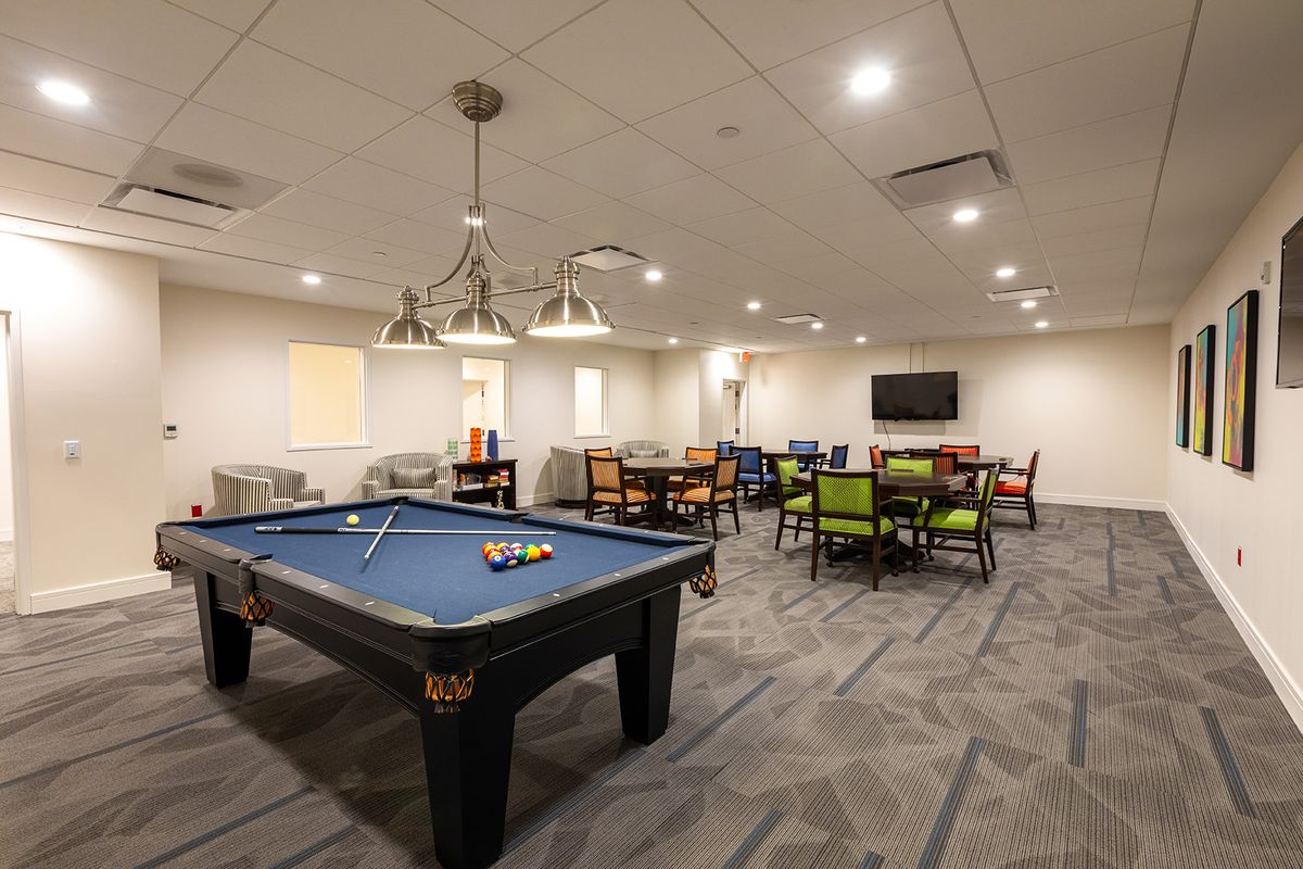 A spacious game room featuring a pool table, seating area, and a television.