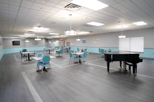An inviting dining hall featuring modern decor with turquoise accents and a grand piano.