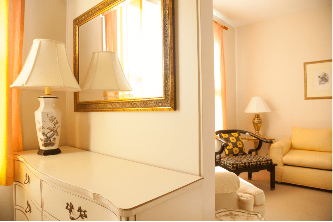A cozy and elegant interior featuring a mirror, lamps, and stylish furniture.