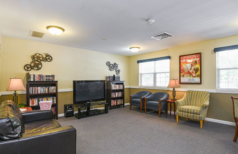 A cozy living room with a television, bookshelves, and comfortable seating.