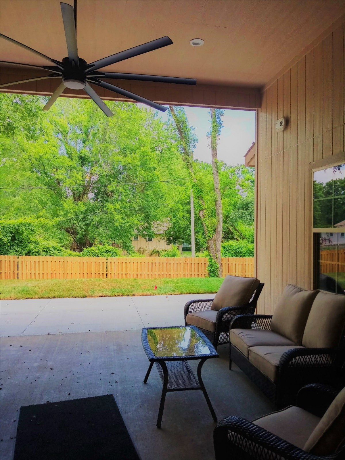 A cozy patio setup with outdoor seating, overlooking a lush green backyard.