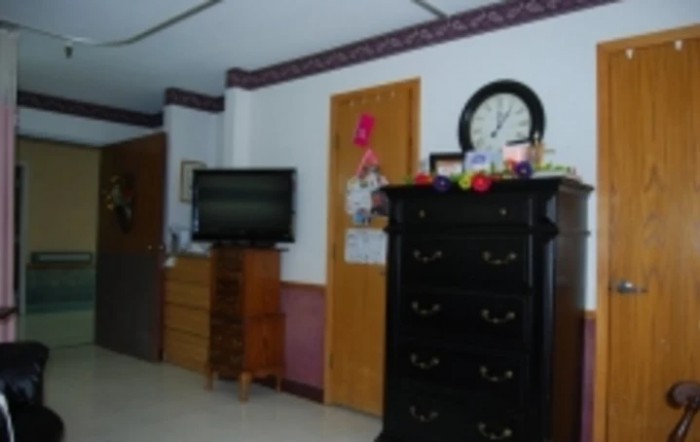 A bedroom with dressers, a television, and a wall-mounted clock.