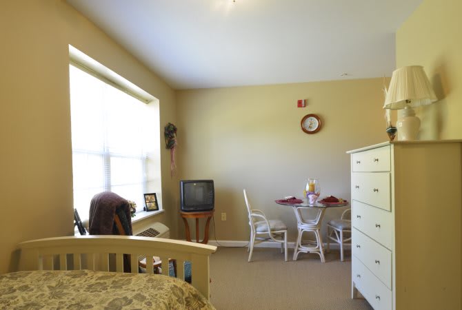 A cozy bedroom with a small dining area and a television.