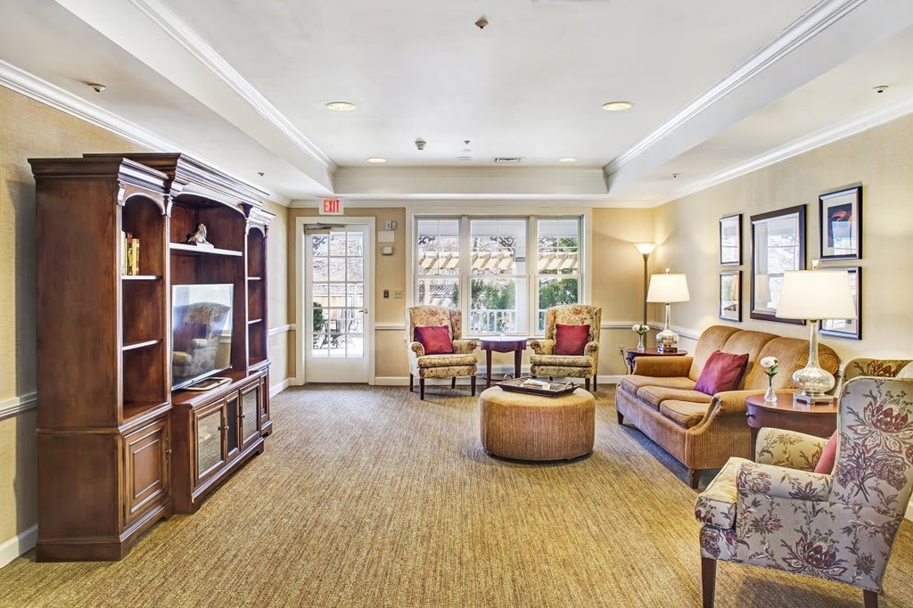 A cozy and bright living room with a sofa, armchairs, and a wooden entertainment center.