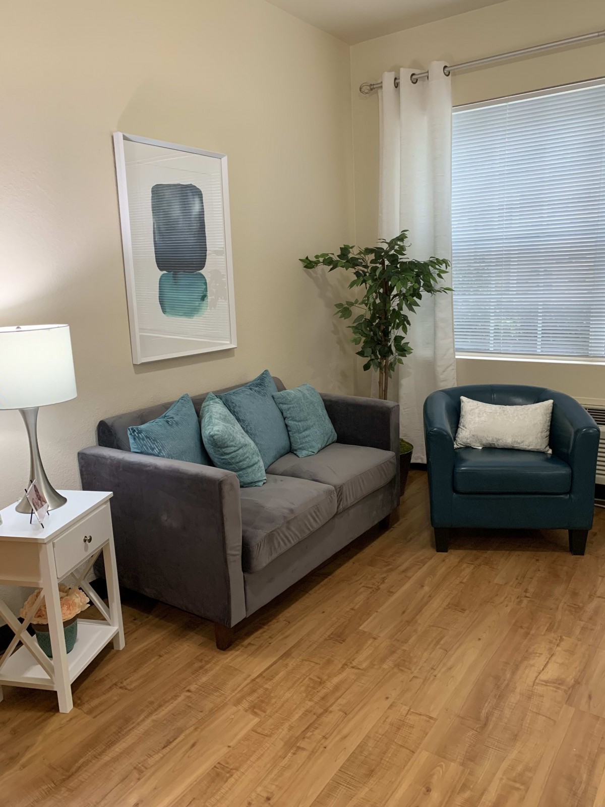 Cozy living room with a grey sofa, teal armchair, and decorative elements.