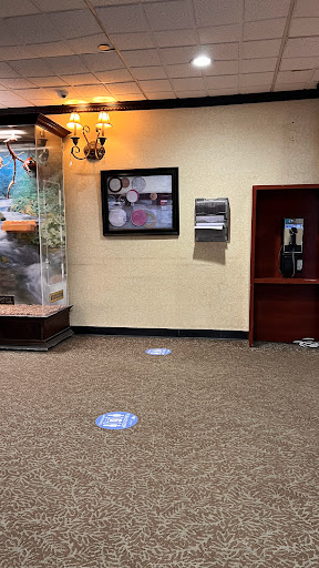A view of a lobby featuring an aquarium, artwork, and a phone booth with floor markings.