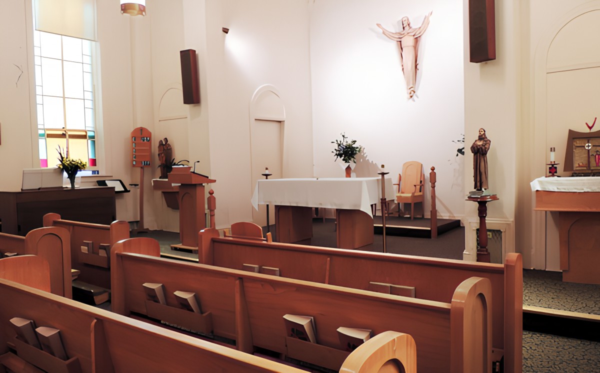 Interior view of a church showing the altar, pews, and a crucifix on the wall.