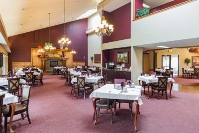 A spacious restaurant dining area with elegantly set tables and grand chandeliers.