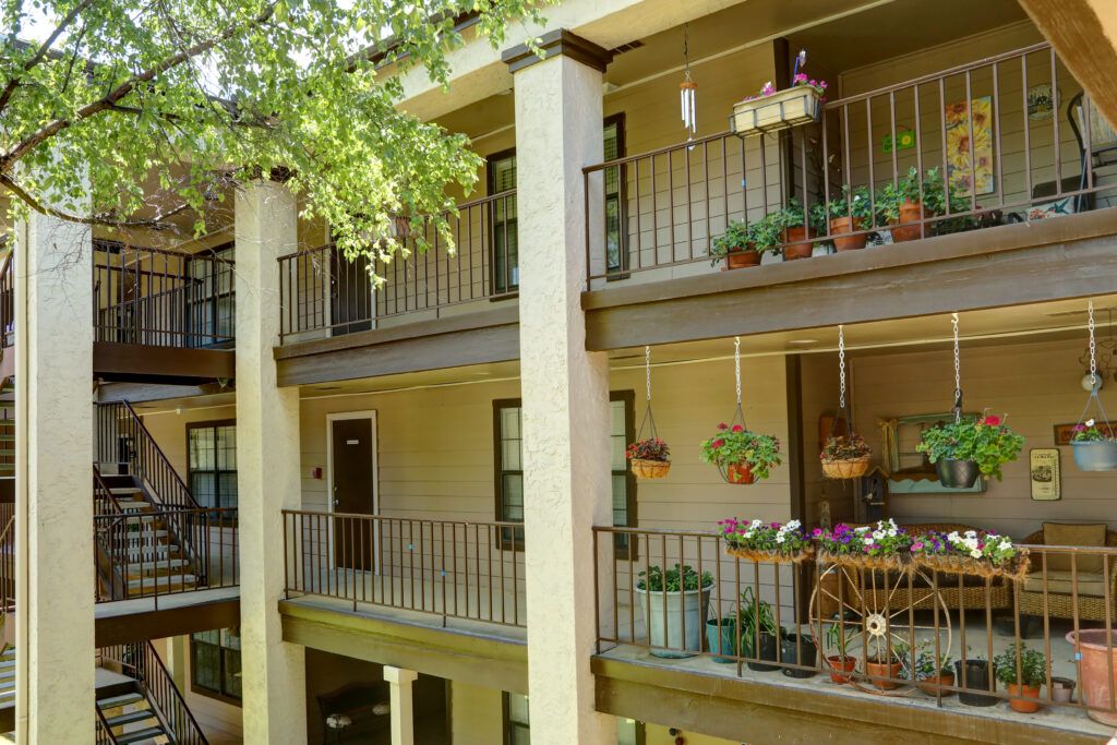 A view of apartment balconies adorned with various plants and hanging baskets.