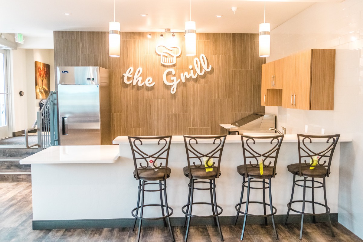 A modern grill restaurant with a sleek bar area and high stools.