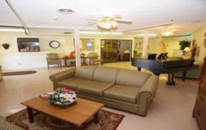 A cozy living room with a sofa, coffee table, and ceiling fan.