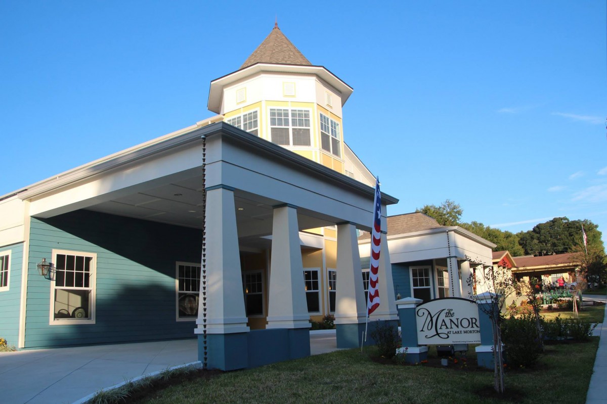 A building with a prominent entrance columns and a sign, featuring a flag on display.