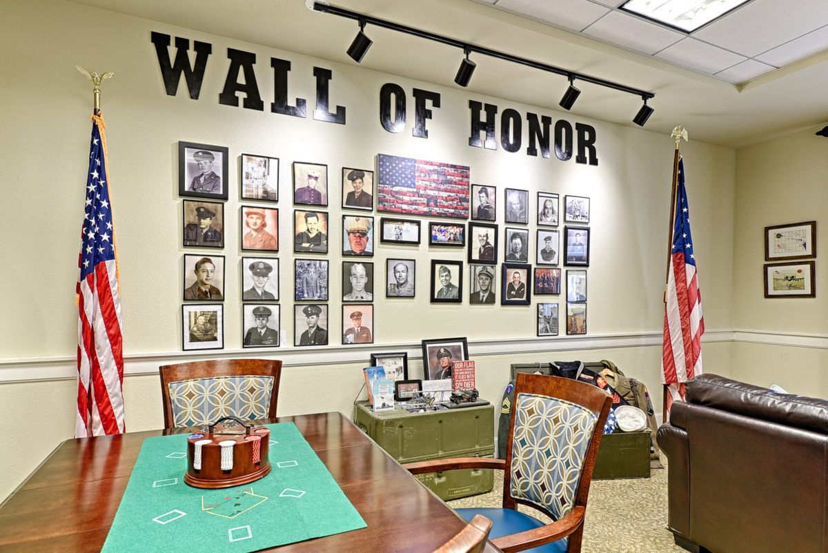 A commemorative Wall of Honor showcasing framed photographs and memorabilia, accompanied by an American flag.