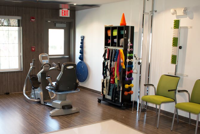 A therapy room with exercise equipment and resistance bands organized on a shelf.