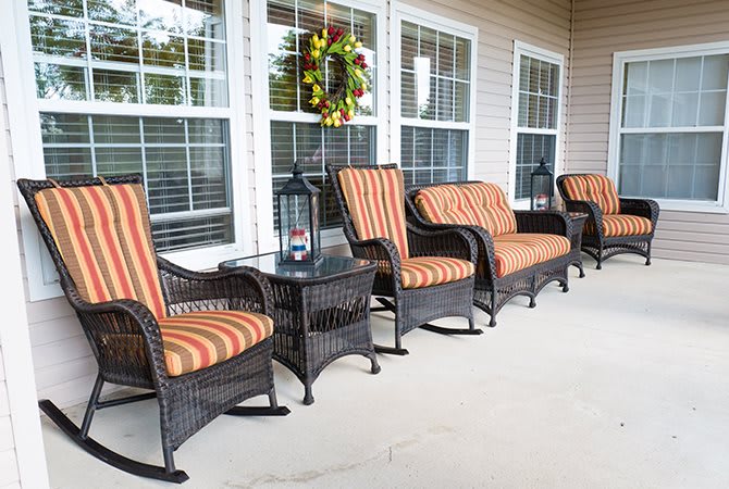 A cozy porch setup with wicker furniture and striped cushions.