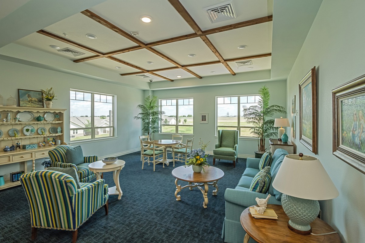 A cozy living room with comfortable seating, tables, and large windows providing ample natural light.